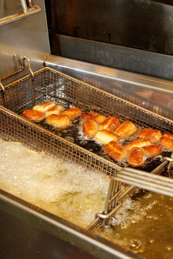 Golden dough frying in a basket in a commercial fryer