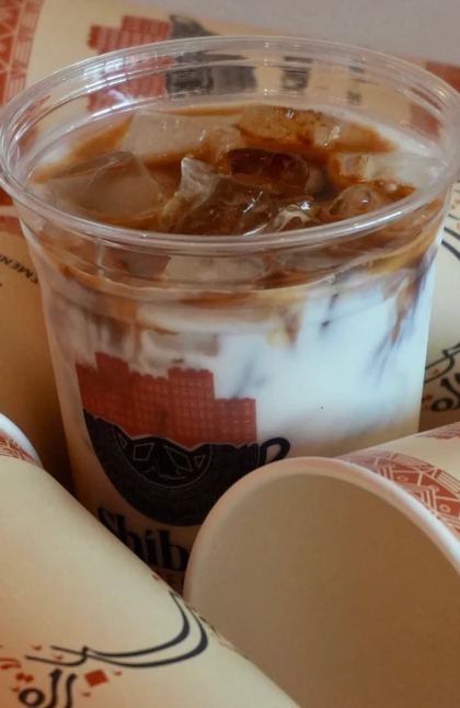 Iced Shibam latte surrounded by patterned Shibam cups