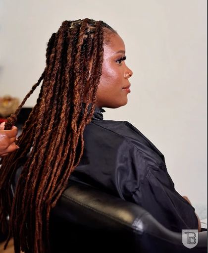 Carousel slide: side profile of a client with long copper locs